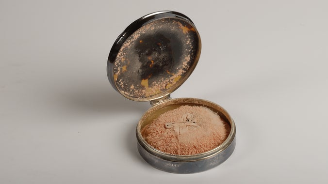 A woman's powder compact dating back to the 20th century with a silver case